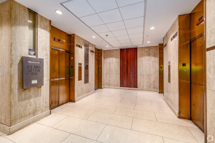 Elevator lobby with bronze doors and travertine walls